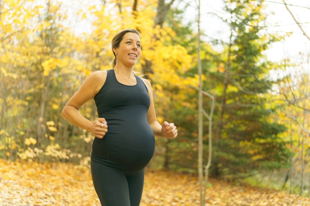 Беременная женщина в черном спортивном костюме на пробежке